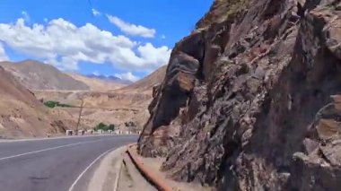 Dik duvarları olan kayalık bir vadi. Varzob geçidinde bir araba yolculuğu. Tacikistan 'a bir gezi. Güzel manzaralı dağ yolu. Gökyüzü mavi ve bulutlar beyaz