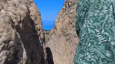 Beşamel Dağı 'na tırmanıyorum. Çiçek desenli yeşil gömlekli bir kadın dar bir kayalık yolda yürüyor. Macera ve keşif ruhu. Azerbaycan, Asya