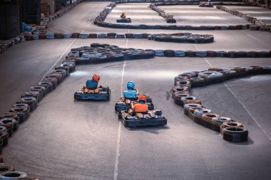 Üç adam kapalı bir karting pistinde birbirini solluyor.