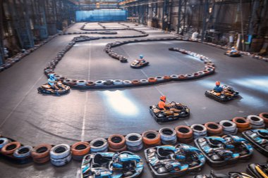 Üç adam kapalı bir karting pistinde birbirini solluyor.
