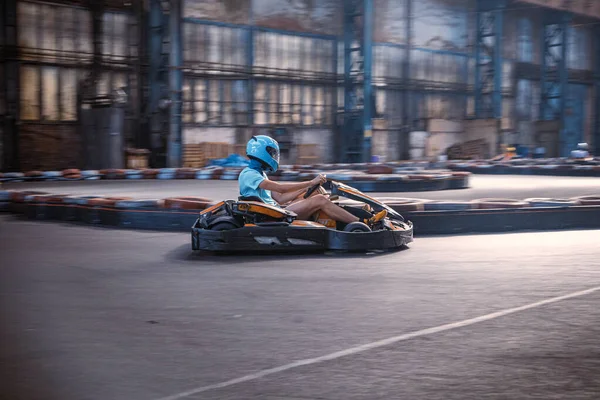 Erkek, kapalı bir pistte kart sürüyor.