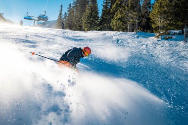 Genç kayakçı yüzünde bir gülümsemeyle fren yapıyor.