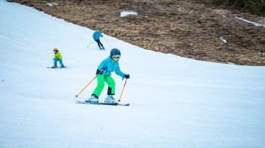 Küçük kız kayak sopalarıyla kaymayı öğreniyor.