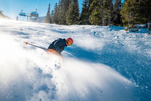 Genç kayakçı yüzünde bir gülümsemeyle fren yapıyor.