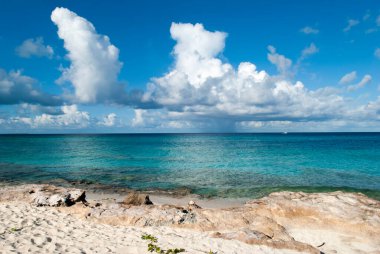 The sunny morning view of rocky beach with rainy clouds in a background on Grand Turk island (Turks and Caicos Islands). 