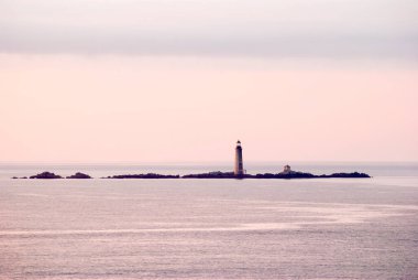 Günbatımından sonra Boston dışında deniz feneri olan bir ada manzarası (Massachusetts). 