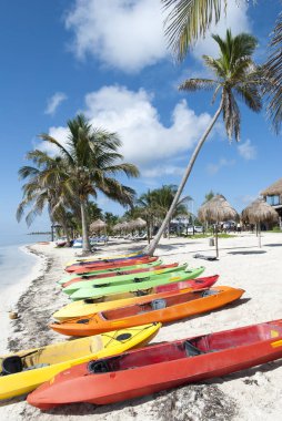Hala boş Mahahual tatil köyü plajındaki renkli kanolar (Meksika)).