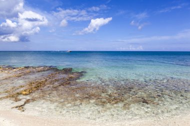 Renkli Grand Cayman adasının manzarası Seven Mile Sahili ve oradan geçen bir motorlu tekne (Cayman Adaları).