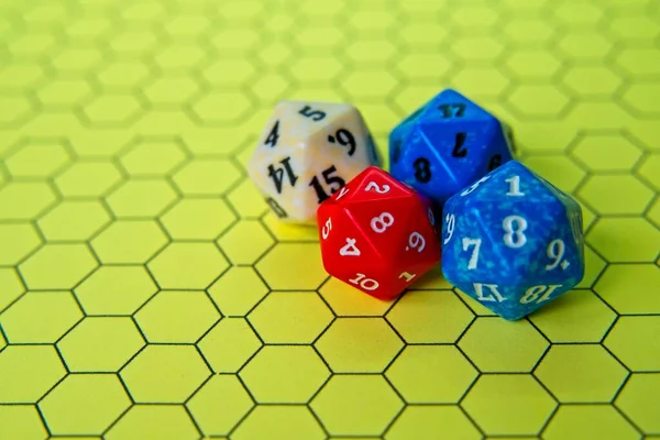 Yellow role-playing board with several colored dice on top in a pentagonal shape