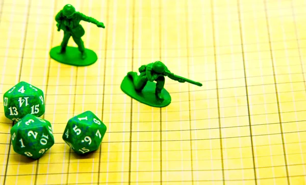 Role-playing field with pentagonal-shaped green dice and miniatures on top of the board