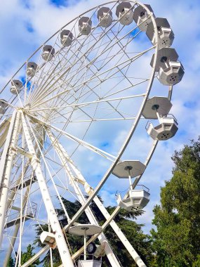 Dönme dolap, beyaz renkli, arkasında mavi gökyüzü olan.