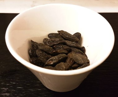 Tonka fasulyesi beyaz kasenin içinde, yukarıdan vurulmuş. Dipteryx odorata, cumaru veya kumaru 'dan Eden. Tohumları tonka fasulyesi, bazen tonkin fasulyesi ya da tonquin fasulyesi olarak bilinir..