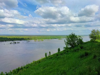Nehrin kenarındaki yeşil dağın tepesinde bulutları olan güzel mavi gökyüzü.