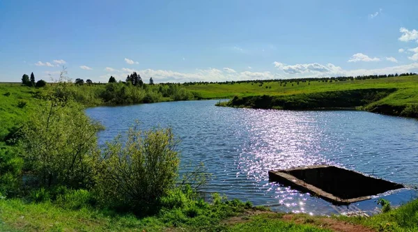 concrete well in a pond in the bright rays of the sun shining on the surface of the water