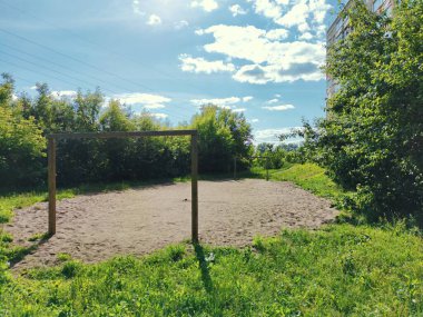 Güneşli bir günde evin yakınındaki yeşil ağaçların arasında terk edilmiş ve boş bir çocuk futbol sahası.
