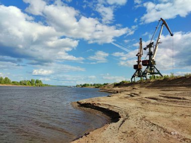 Nehrin kumlu kıyısında iki vinç bulutlu güzel mavi bir gökyüzüne karşı