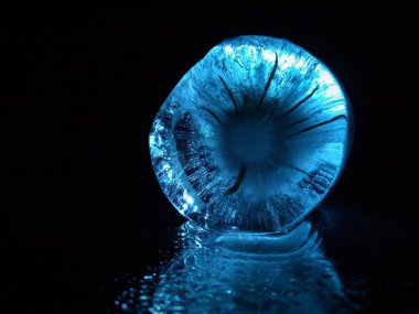 Karanlıktaki bir buz parçası yaratıcı bir fotoğrafta mavi parlar.