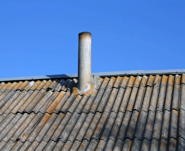 A chimney on an old moss-covered roof.