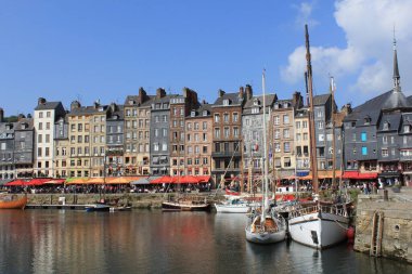 Fransa 'nın Honfleur limanında yazın büyük kasaba evleri ve marinada renkli balıkçı tekneleri.