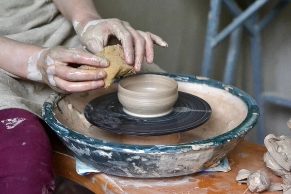 person potter makes clay jug on a potters wheel