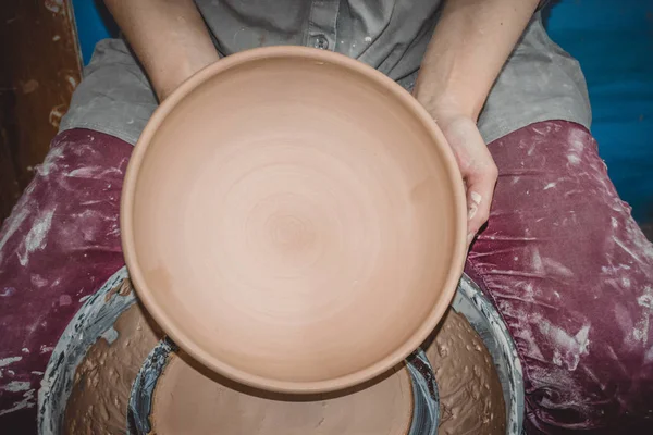 Potter holds round clay plate in his hands. — Stock Photo, Image