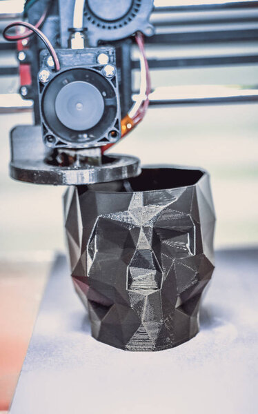 3D принтер печатает модель в виде черного черепа крупным планом
.