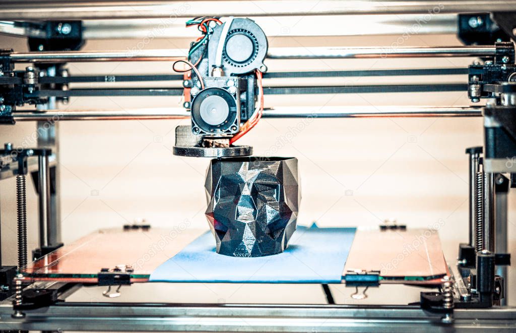 3D printer printing a model in the form of black skull close-up.