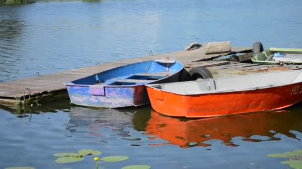 Een paar oude shabby en versleten boten verschillende kleuren op de pier van dok — Stockvideo