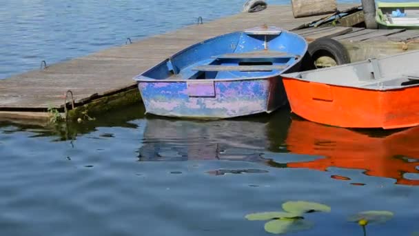 A few old shabby and worn boats different colors on the dock pier — Stock Video