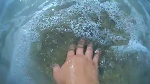 Meisjes hand ligt op zand strand en zee Golf is glooiende close-up. — Stockvideo