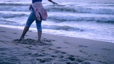 Denize bir kız kot ve onun kemer bağlı pembe bir ceket geldi