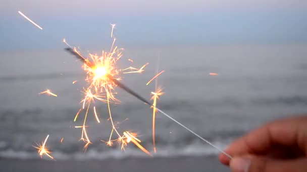 Bruciare un fuoco del Bengala in mano sullo sfondo di un mare — Video Stock