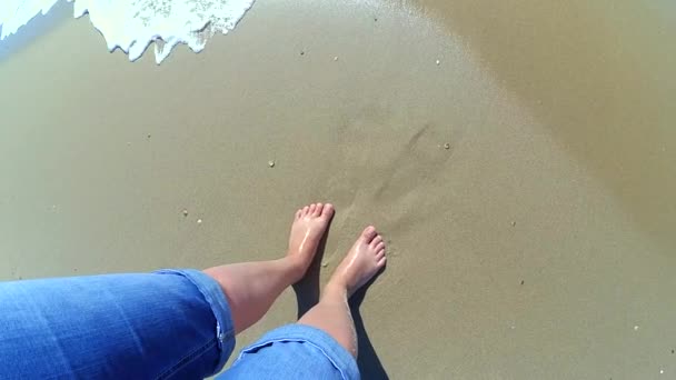 The girl is standing near the sea and waves roll her on her feet — Stock Video