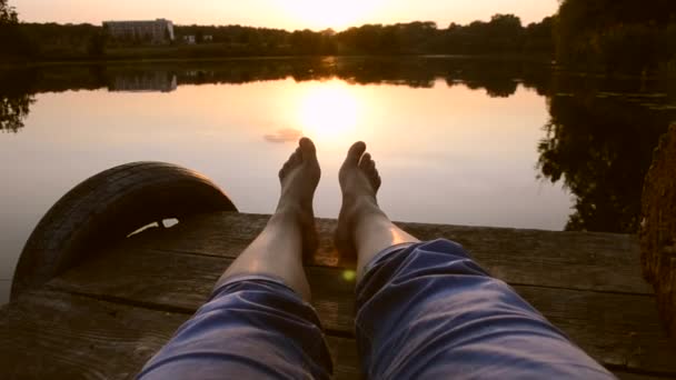 Ноги лежат на пирсе у озера. — стоковое видео