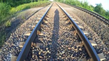 Bir demiryolu üzerinde yürüyen bir adam gölgesi.