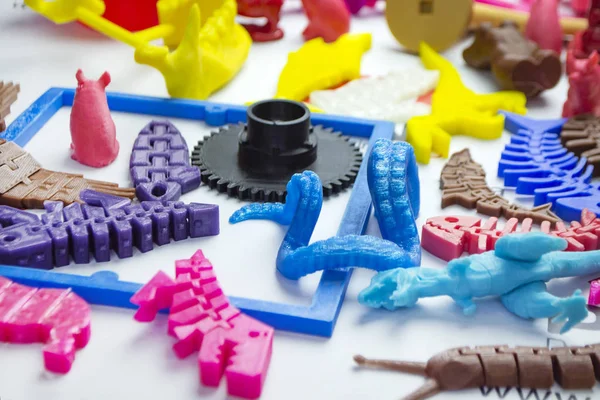 Many bright multi-colored objects printed on 3d printer lie on flat surface — Stock Photo, Image