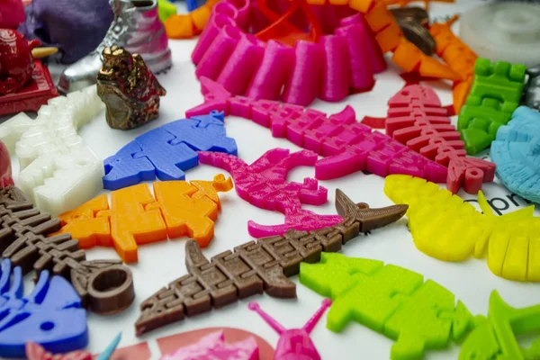 Molti oggetti multicolori luminosi stampati su stampante 3d si trovano sulla superficie piana — Foto Stock