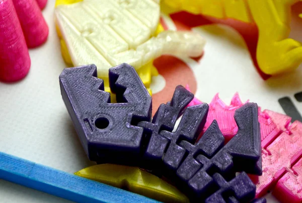 Many bright multi-colored objects printed on 3d printer lie on flat surface — Stock Photo, Image