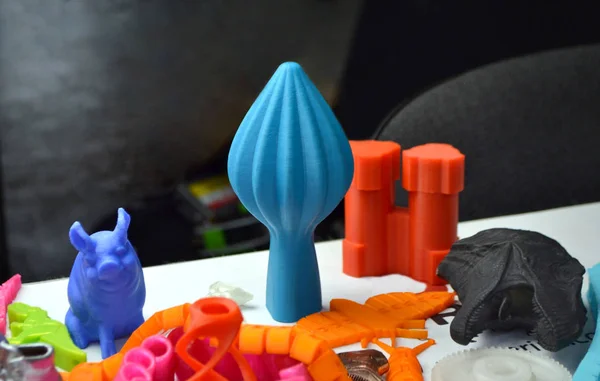 Mnoho pestrobarevných objektů vytištěných na 3D tiskárně leží na plochém povrchu — Stock fotografie