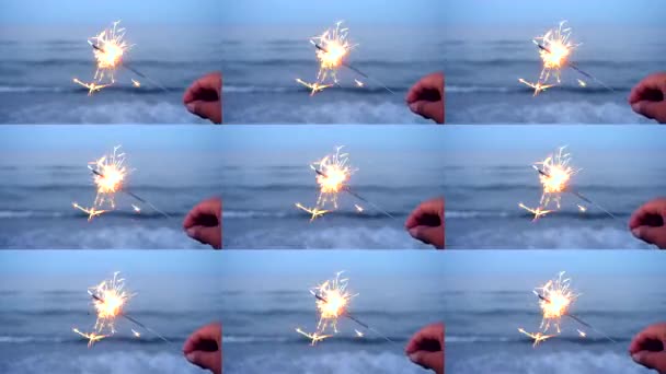 Ein bengalisches Feuer in der Hand vor dem Hintergrund der Meereswellen — Stockvideo