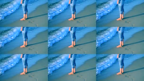 Flickan står nära havet och vågorna rulla henne på hennes fötter — Stockvideo