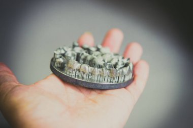 Metal 3D yazıcıya yazdırılmış nesneyi tutan adam.