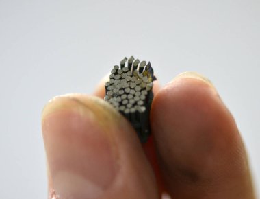 Bir adam elinde bir nesne metal yazdıran bir 3d yazıcıda yazdırılan tutar