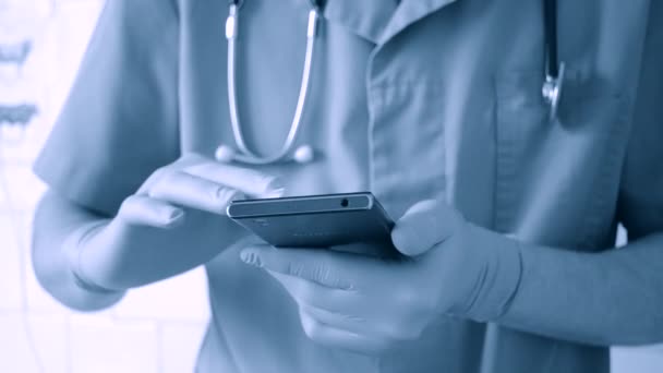 Doctor en guantes azules y azul corre en un teléfono móvil — Vídeo de stock