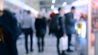 Bulanık arka plan akışını alan alışveriş merkezi içinde birçok kişi