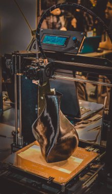 3D yazıcı siyah vazo gibi yakın plan bir model yazdırıyor.