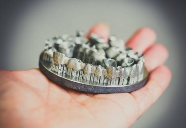 Metal 3D yazıcıya yazdırılmış nesneyi tutan adam.