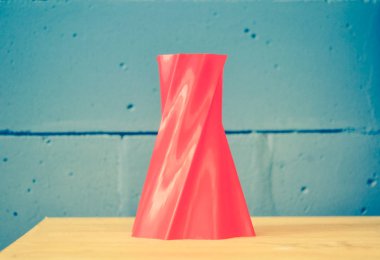 Mavi tuğla duvara 3D yazıcı tarafından basılan parlak kırmızı nesne vazosu 