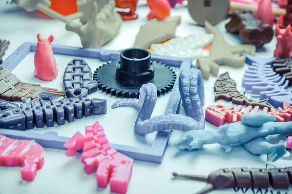 Many bright multi-colored objects printed on 3d printer lie on flat surface — Stock Photo, Image