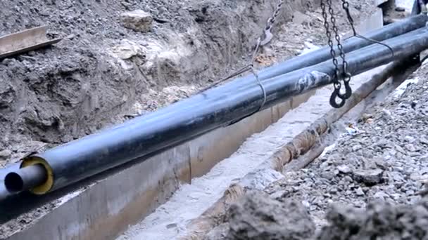 Los trabajadores ponen tubos con una grúa de construcción en el suelo — Vídeo de stock